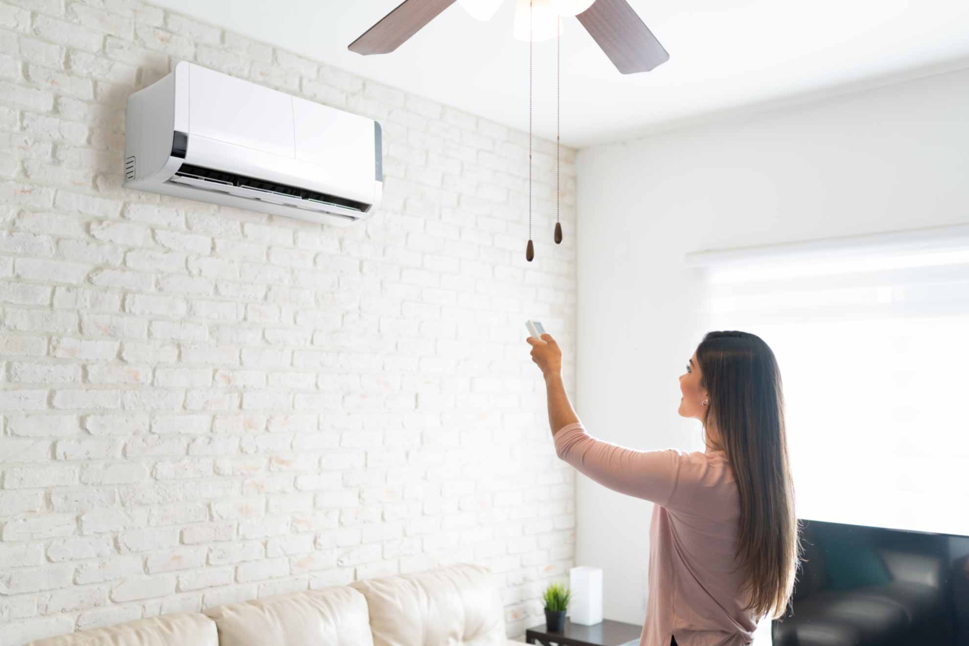 Woman turning on AC unit with remote